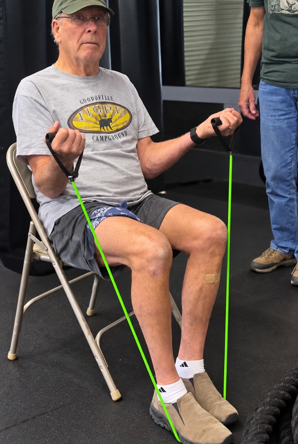 Seated senior member exercising with green resistance bands